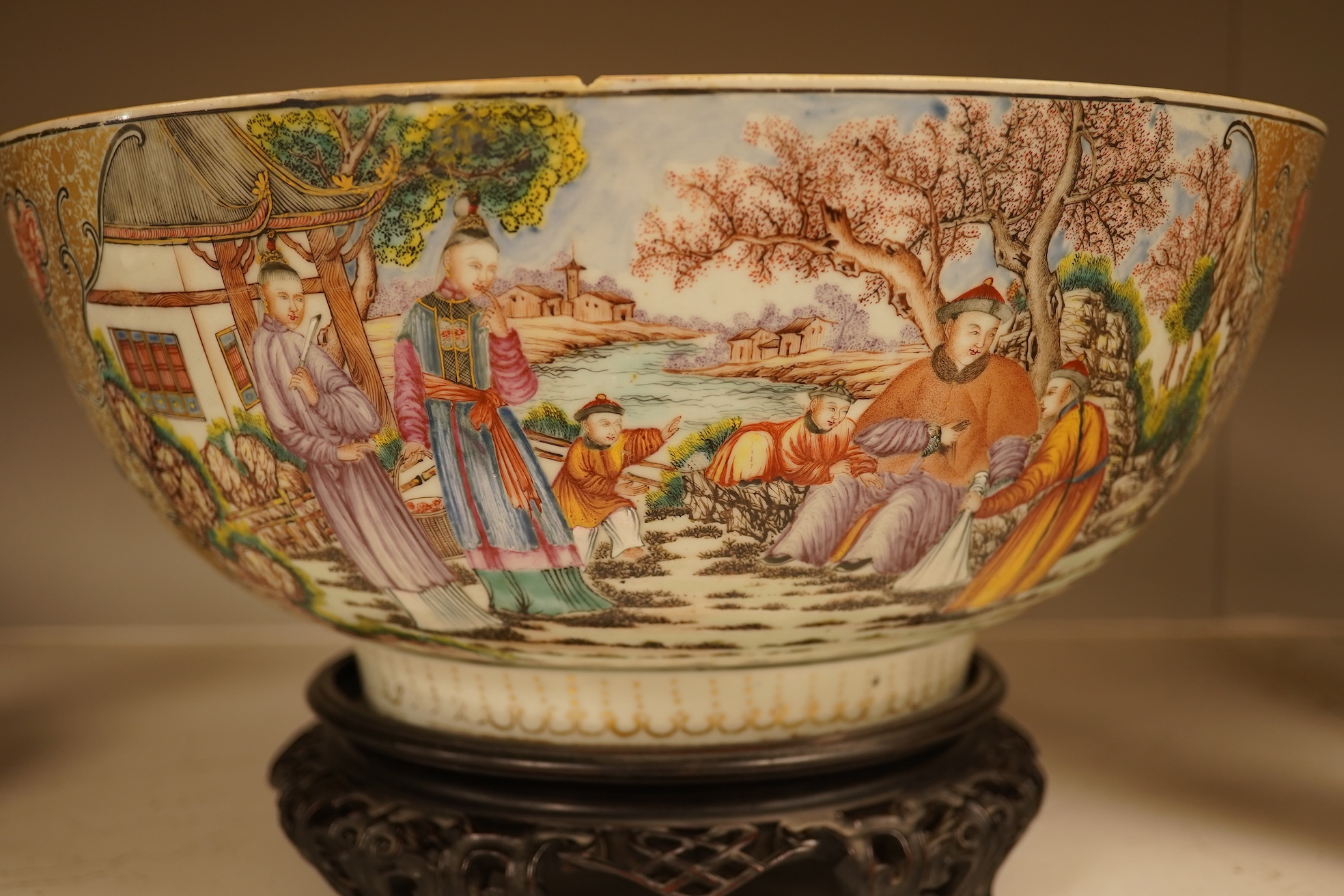 An 18th century Chinese famille rose figural bowl, on wooden stand, 34cm diameter.